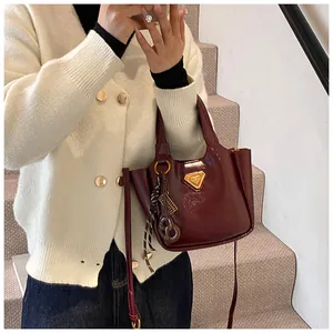Close-up of glossy burgundy bucket bag with golden triangle logo and shoulder strap