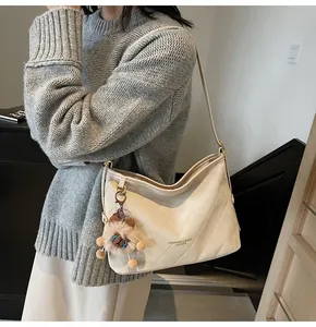 Détail du sac cabas matelassé blanc cassé avec breloque lion porté par un mannequin