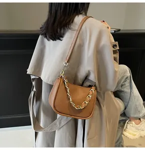 Détail du sac en cuir caramel montrant le grain de cuir et la chaîne dorée