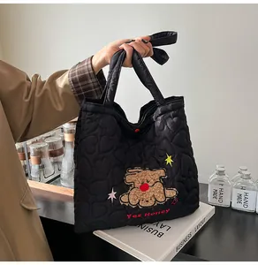 Dettaglio borsa shopper nera trapuntata a cuore con patch di cane e ricamo