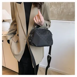 Détail du sac bandoulière en nylon noir avec monogramme ELB et finitions argentées