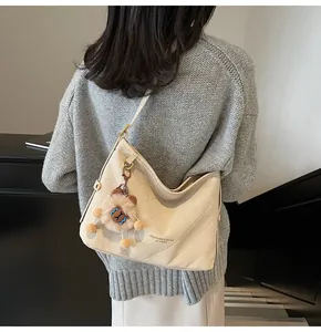 Détail du sac fourre-tout matelassé avec pendentif lion porté par un mannequin