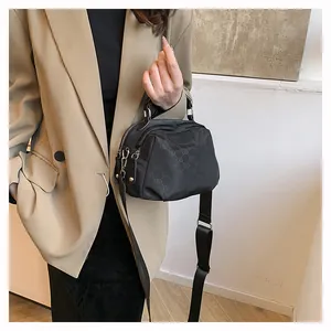 Détail du sac à bandoulière en nylon noir avec motifs de lettres et sangle large