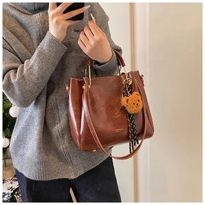 Detail view of brown faux leather tote with metal ring handles and plush bear charm