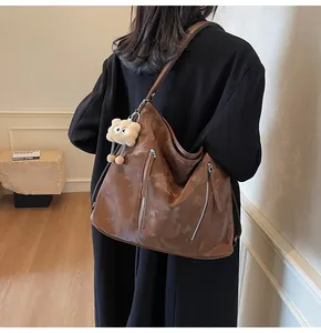 Brown vintage faux leather tote bag with silver zippers and plush monster charm