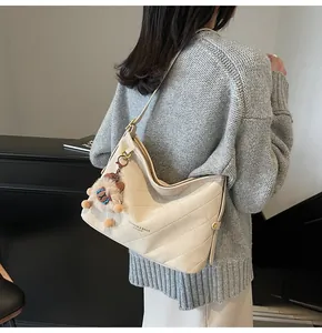 Vue latérale du sac cabas matelassé crème avec boucle dorée et breloque peluche ours
