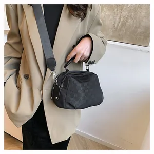 Détail d'un sac bandoulière en nylon noir avec motif monogramme ELB et bandoulière large