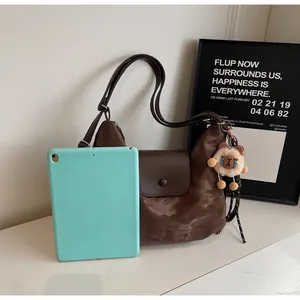 Detail der dunkelbraunen Totebag mit Bärenanhänger zeigt Kapazität neben Tablet