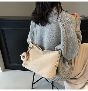Détail d'un sac cabas matelassé crème avec un charmant lion en peluche sur le côté