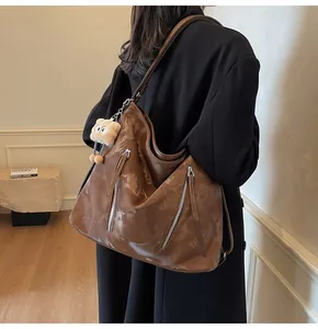 Side view of vintage brown tote bag with zipper details and cute bear charm on model