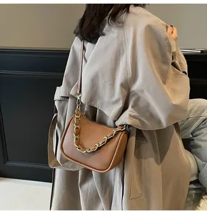 Détail de la texture en cuir marron et de la chaîne dorée du sac à main en demi-lune