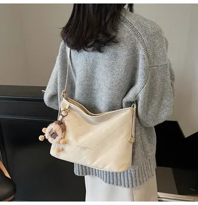 Détail du sac à bandoulière matelassé blanc cassé avec breloque lion et imprimé