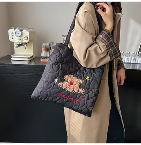 Dettaglio della borsa tote nera trapuntata a cuore con ricamo di orsetto e scritta