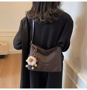 Détail du cabas matelassé marron avec logo doré et breloque lion en peluche sur modèle