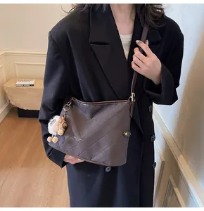 Détail du sac cabas matelassé marron foncé avec logo et charmant pendentif en peluche
