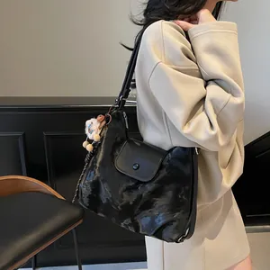 Schwarze gesteppte Tote Bag für Damen mit Fronttasche und Anhänger am beigen Outfit