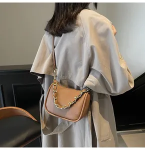 Détail d'un sac à bandoulière en cuir marron grainé avec une chaîne dorée épaisse