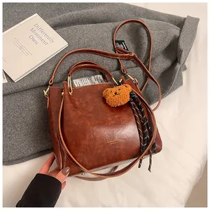 Detailed view of vintage brown PU leather handbag with teddy bear charm and strap