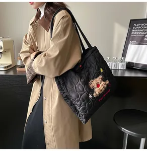 Dettaglio della borsa tote nera trapuntata a cuori con ricamo di orsetto e scritta