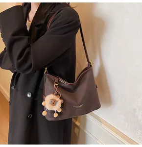Détail du sac cabas matelassé marron foncé avec couture en losange et pendentif peluche