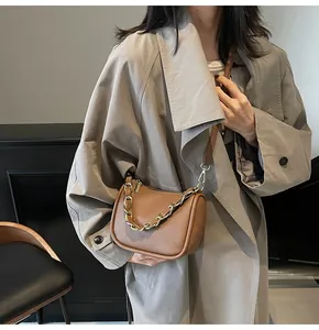 Détail du sac en cuir texturé caramel avec chaîne dorée épaisse porté par un modèle