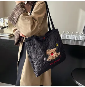 Dettaglio del ricamo a forma di orso e cuciture a cuore su questa borsa trapuntata nera