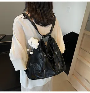 Detail of black pleated nylon tote bag with dual zippers and plush cloud pendant charm