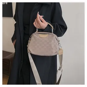 Détail du sac bandoulière en nylon beige avec motif ELB et large bandoulière textile