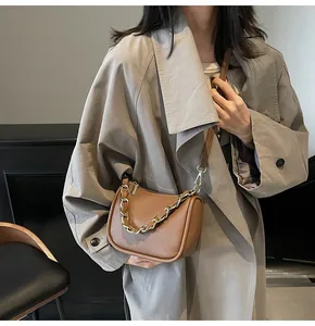 Détail du sac bandoulière en cuir marron à motif litchi avec chaîne dorée et lanière