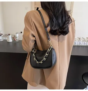Détails du sac en cuir grainé noir avec chaîne en métal doré et bandoulière fine