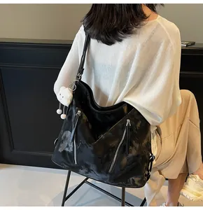 Detail of a black oversized faux leather hobo bag featuring a cute white cloud pendant