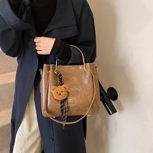 Dark brown large capacity shoulder bag with bear charm and striped ribbon detail