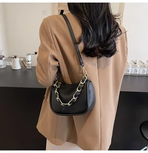 Détail du sac bandoulière en cuir grainé noir avec chaîne décorative dorée épaisse