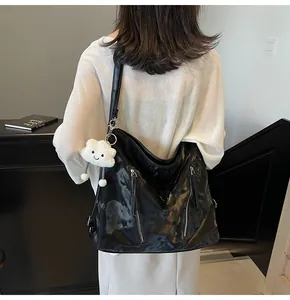 Detail of large black tote bag with metal zippers and a cloud plush charm on a model