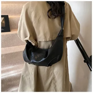 Detail of black crescent moon bag with knotted shoulder strap worn with a trench coat
