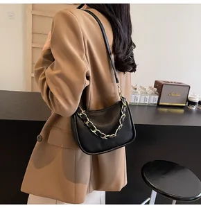 Vue latérale du sac hobo en cuir noir avec chaîne dorée et fine bandoulière en cuir