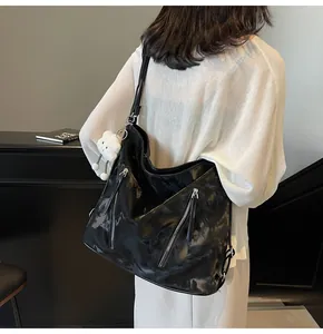 Side view of a large black faux leather tote bag with silver zippers and plush charm