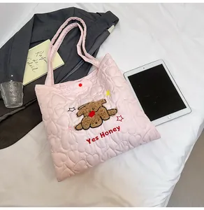 Dettaglio della borsa tote rosa trapuntata con cuori e toppa in peluche a forma di cane
