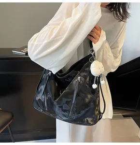 Close-up of black leather tote bag with vertical zippers and white plush charm on model