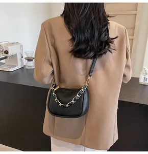 Détail d'un sac à bandoulière en cuir noir avec chaîne dorée et fermeture éclair