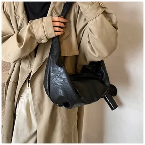 Detail of black oversized slouchy leather shoulder bag paired with a khaki trench coat
