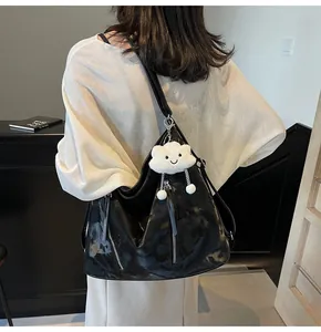 Detail of glossy black tote bag with silver zippers and a cute cloud plush charm