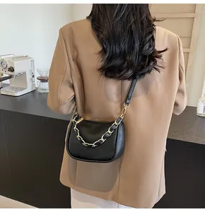 Détail du sac demi-lune en cuir noir grainé avec chaîne dorée porté par un mannequin