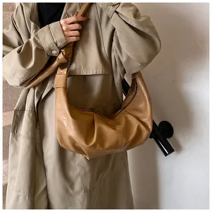 Detail of khaki crescent leather shoulder bag with aesthetic pleats and soft texture
