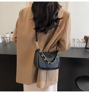 Détail du sac bandoulière en cuir grainé noir avec grosse chaîne dorée et finition élégante