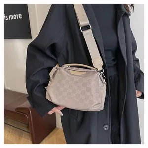 Détail d'un sac bandoulière en nylon beige avec imprimé lettres ELB et large bandoulière