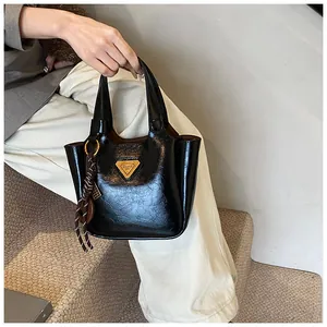 Close-up of black leather bucket bag with golden triangle logo and woven tassel detail