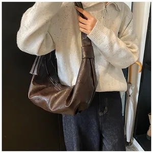 Close-up of vintage brown oversized hobo bag showing pleated faux leather texture and wide strap