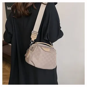 Sac bandoulière en nylon kaki avec imprimé monogramme porté par un mannequin