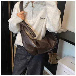 Detail of a large brown hobo bag featuring retro leather texture and knot shoulder strap